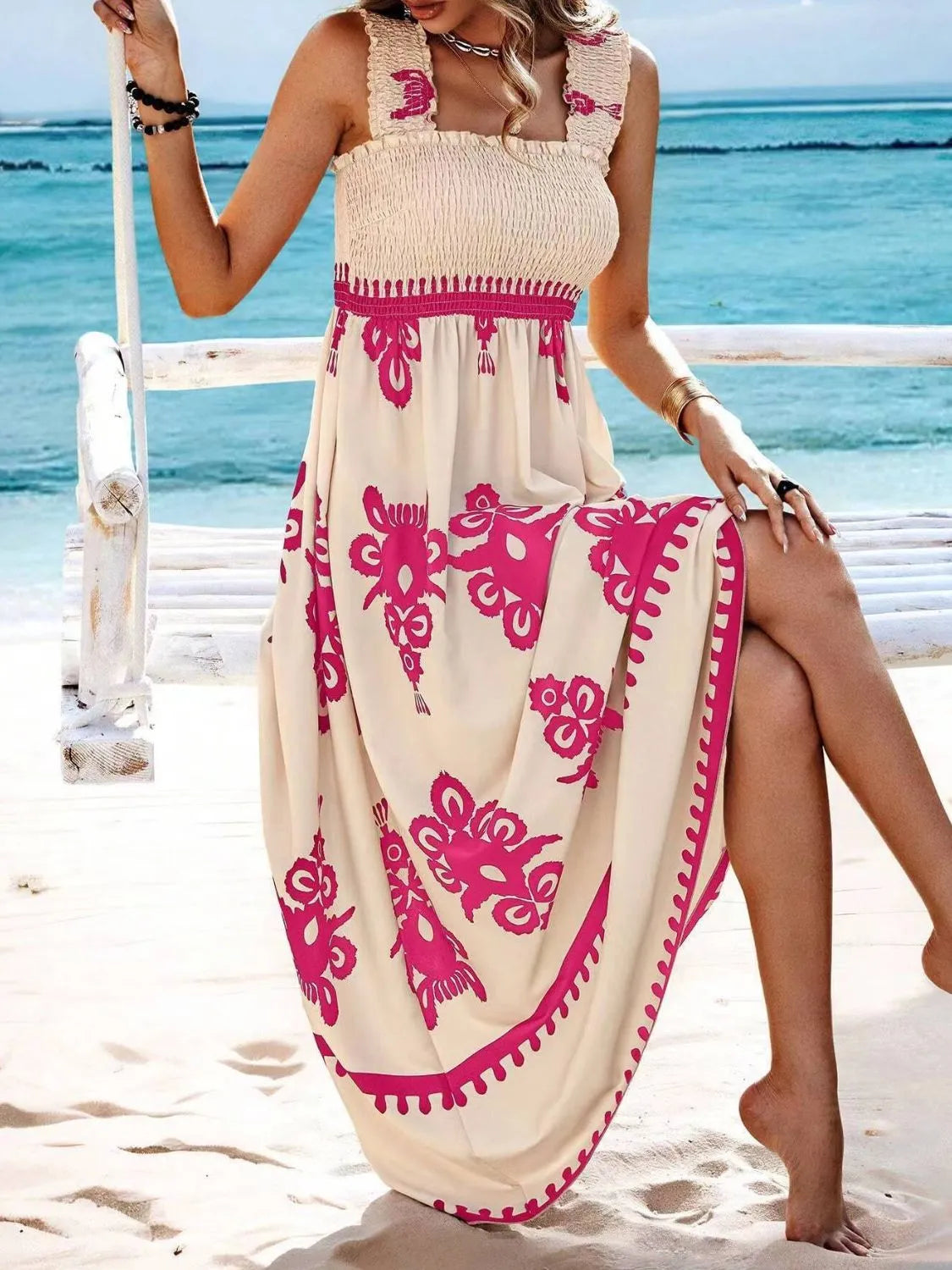 Trendsi Smocked Printed Maxi Dress with Wide Straps elegantly styled at the beach, emphasizing its fashionable cream and pink floral details, perfect for summer occasions.