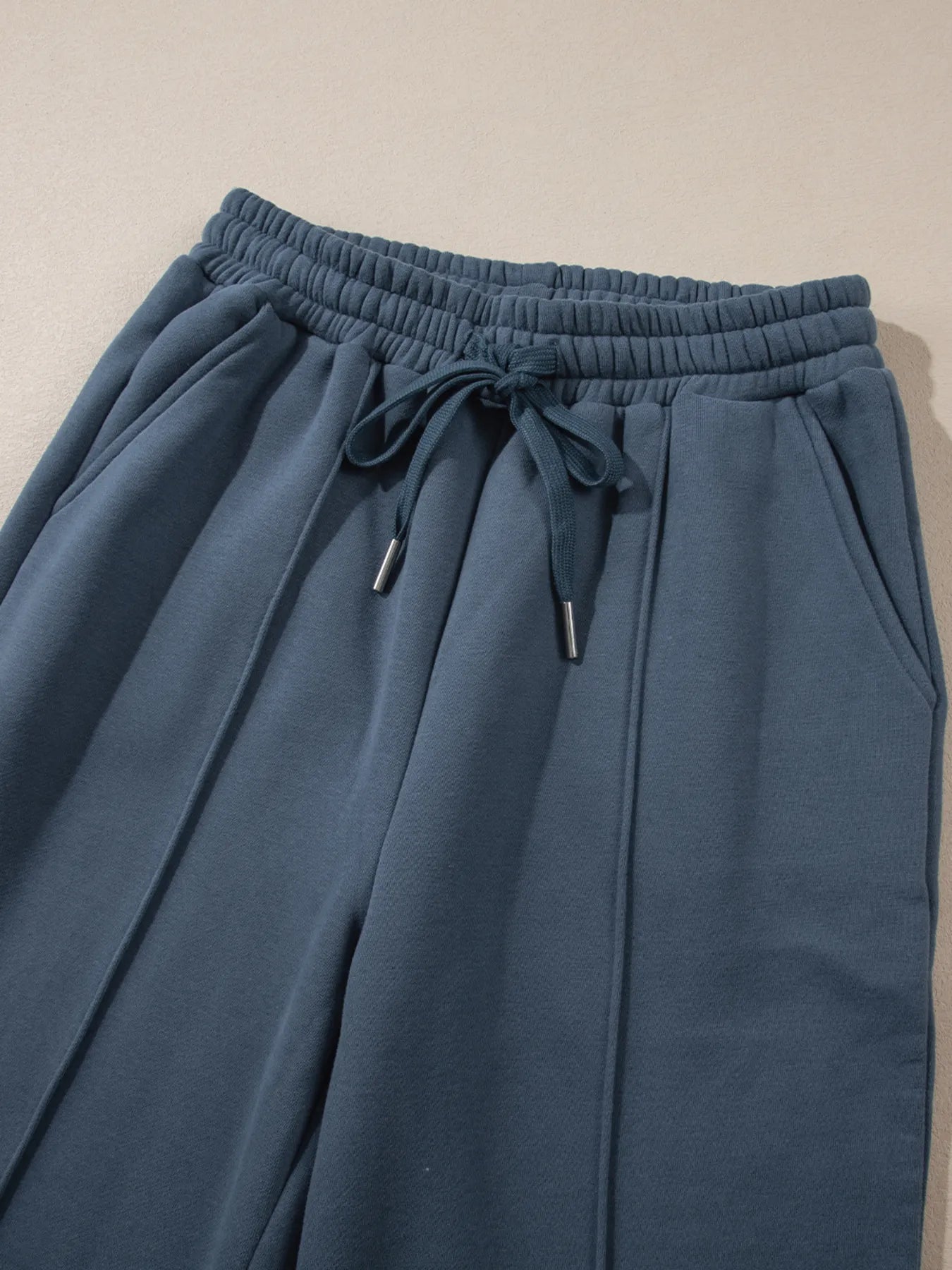 Detail of the high waist pants from the Trendsi Collared Sweatshirt & High Waist Pants Two-Piece Active Set - Soft Cotton Blend, featuring a drawstring and pockets.