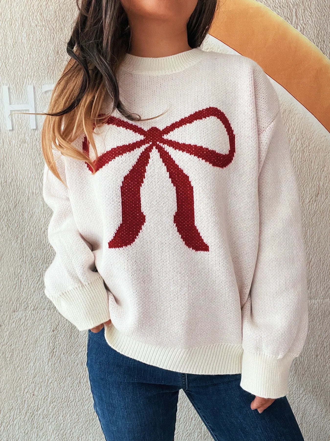 Stylish Bow Pattern Casual Long Sleeve Sweater for Effortless Everyday Wear, featuring a red bow design on a light pink background, modeled casually with dark jeans.