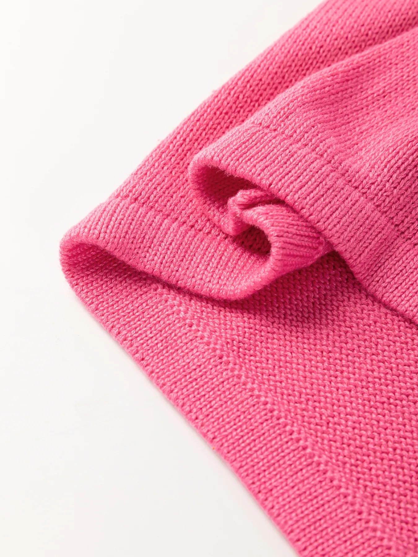 Folded detail of the Stylish Contrast Trim Pearl Detail Sweater Tank Top, emphasizing the sleek design and cozy pink knit.