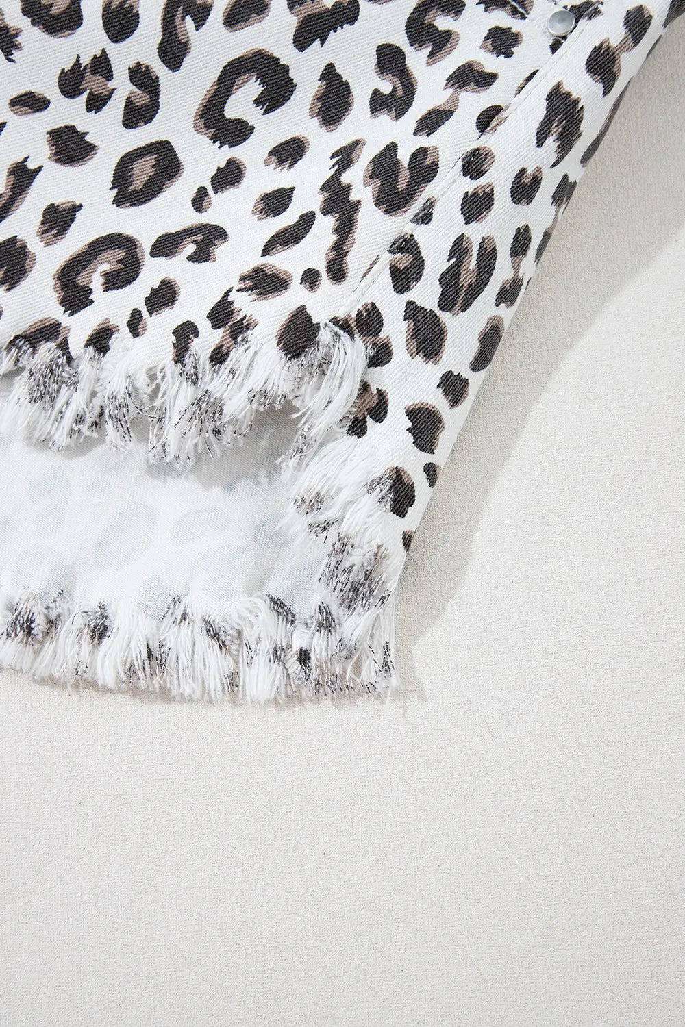 Close-up of Leopard Frayed Hem Denim Shorts - Detail of frayed hem and leopard pattern fabric.