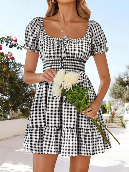 Close-up view of Women’s Gingham Puff Sleeve Smocked Dress, highlighting the ruffled hem and chic black and white gingham pattern, perfect for summer.