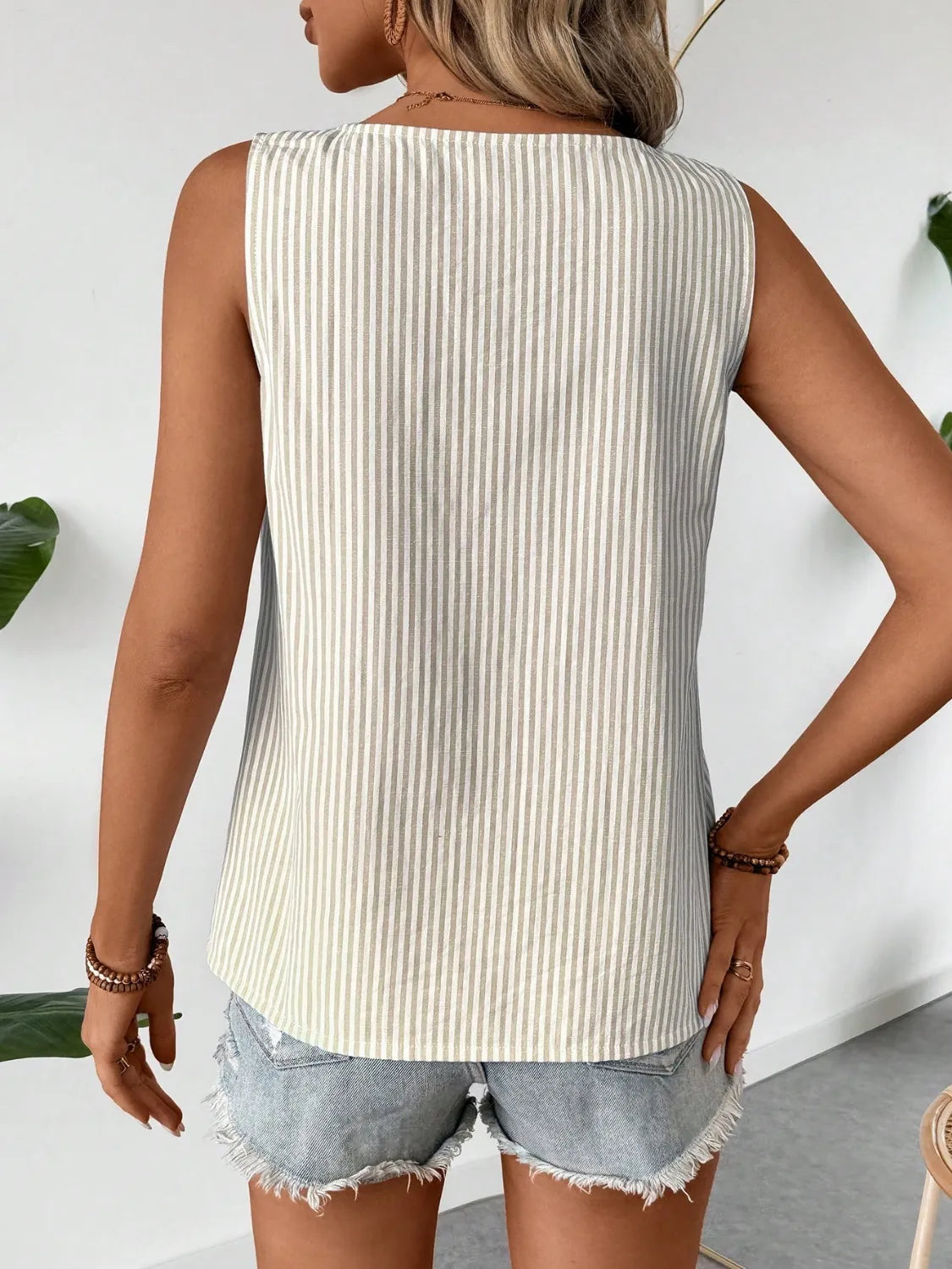 Back view of the Asymmetrical Striped Tank with Decorative Buttons for Women, showcasing its light stripes and relaxed fit, made of 100% polyester.