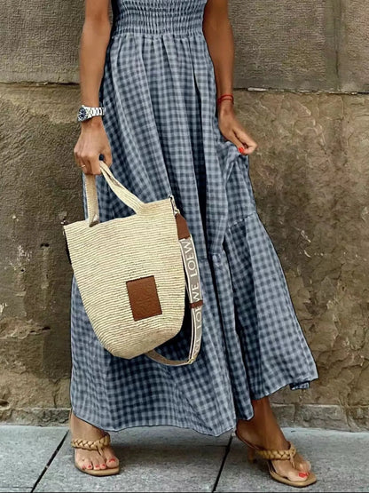 Detail shot of a Gingham Maxi Dress with Ruffle Straps, Smocked Bodice & Tiered Design by Trendsi, highlighting the flowy skirt and stylish straw bag.