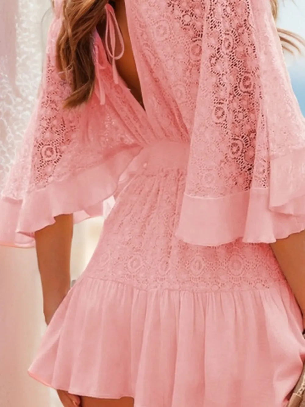 Close-up of the back detail of the Semi-Sheer Ruffle Hem Lace Mini Dress with Tie Back - Elegant Smocked Design, showcasing delicate lacework and a flowing pink fabric.
