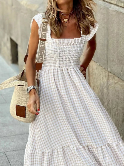 Chic female model in a Gingham Maxi Dress with Ruffle Straps, Smocked Bodice & Tiered Design by Trendsi, strutting her style with a textured bag on the street.